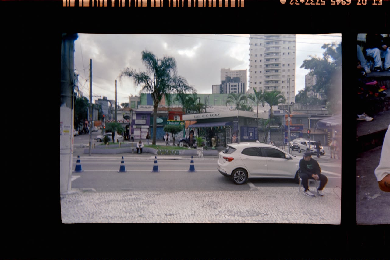 Esquina de rua com carro branco e cones de trânsito